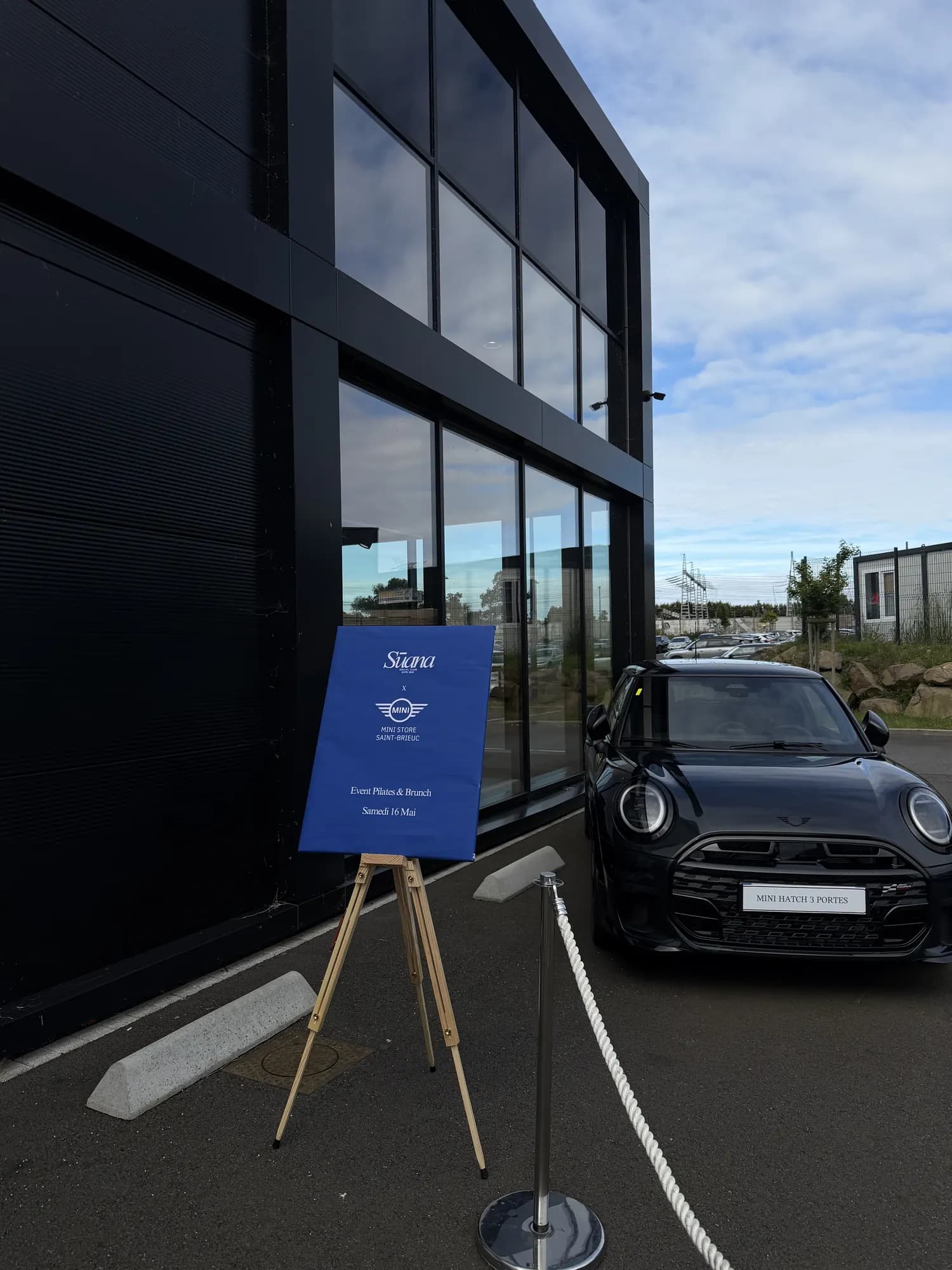 Chevalet Sūana × MINI devant une voiture dans la concession BMW MINI